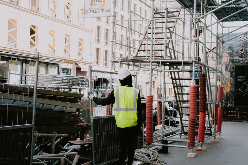 pracownik budowlany weryfikujący stabilność konstrukcji rusztowaniowej na placu budowy